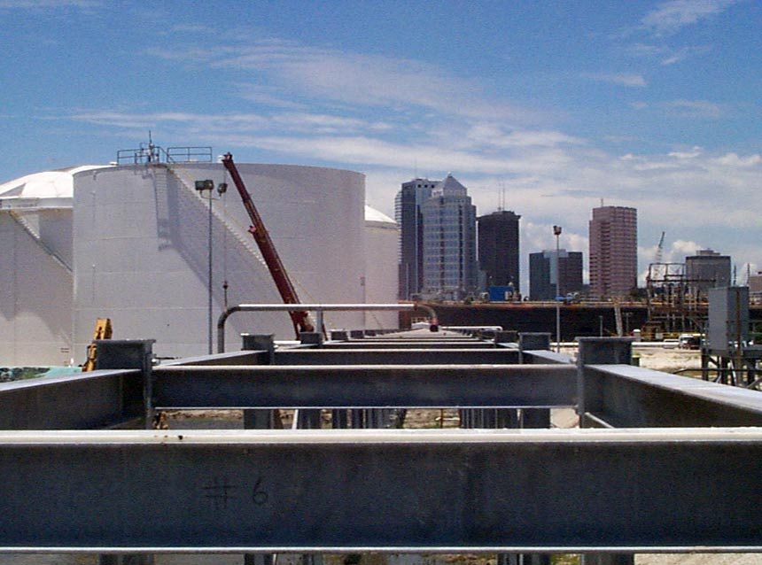 Steel pipe supports at a Tampa fuel terminal with the downtown skyline in the distance