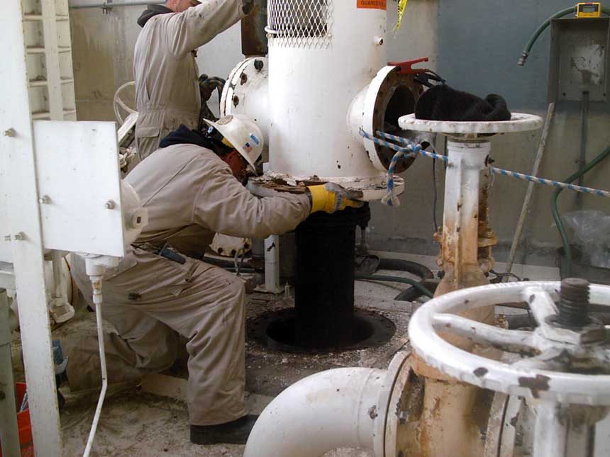 Worker in a hard hat connecting a pipe fitting inside a fuel terminal